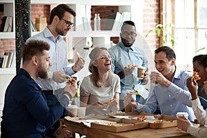 Happy diverse team people talking laughing eating pizza in office