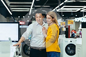 Happy diverse young family man and woman choose electronic household appliances