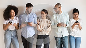 Happy diverse young people using different electronic devices.