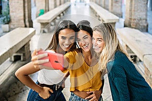Happy diverse young woman friends enjoying time taking selfie with phone