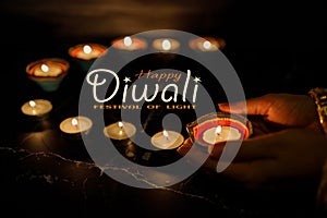 Happy Diwali - Woman hands with henna holding lit candle isolated on dark background