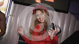 Happy dj girl in red dress with rim on head jump at turntable in club. Breast