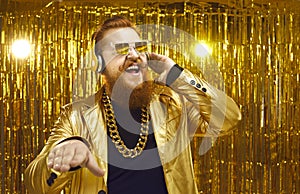 Happy DJ in shiny jacket, headphones and cool sunglasses playing music at disco party