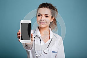 Happy doctor with stethoscope showing blank smartphone screen