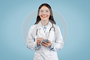 Happy doctor texting on smartphone and smiling