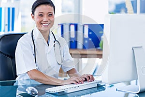 Happy doctor using her computer and looking at camera