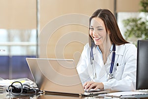 Happy doctor using a laptop at consultation photo