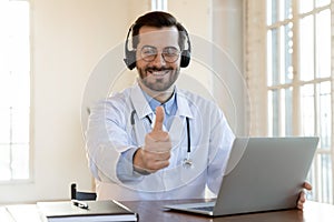 Happy doctor in wireless earphones recommending contact to medical hotline