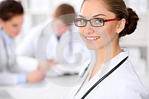 Happy doctor woman with medical staff at the hospital sitting at the table