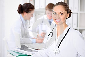 Happy doctor woman with medical staff at the hospital sitting at the table