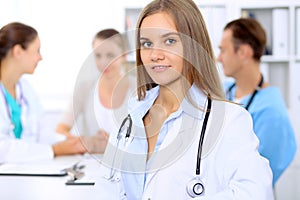 Happy doctor woman with medical staff at the hospital sitting at the table