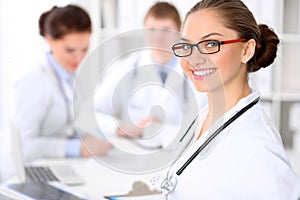 Happy doctor woman with medical staff at the hospital sitting at the table