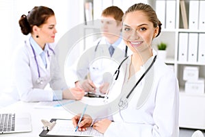 Happy doctor woman with medical staff at the hospital sitting at the table