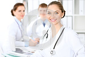 Happy doctor woman with medical staff at the hospital sitting at the table