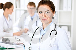 Happy doctor woman with medical staff at the hospital sitting at the table photo