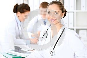 Happy doctor woman with medical staff at the hospital sitting at the table