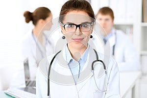 Happy doctor woman with medical staff at the hospital sitting at the table