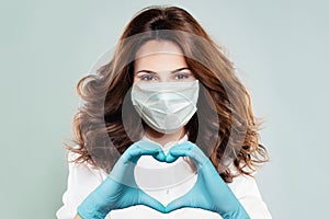 Happy doctor woman in protective mask making heart. Healthcare, medicine and treatment concept