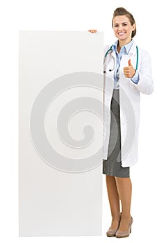 Happy doctor woman showing blank billboard
