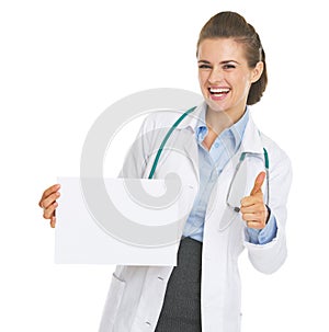 Happy doctor woman showing blank paper sheet and thumbs up