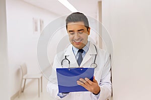 Happy doctor writing to clipboard at hospital