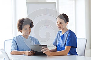 Happy doctors with tablet pc meeting at hospital