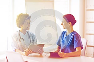 Happy doctors with tablet pc meeting at hospital