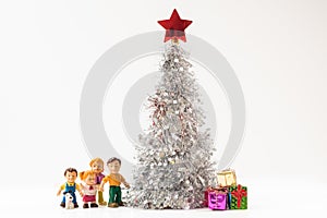 happy doll family with a puppy and colorful gift boxes under the lush silver Christmas tree