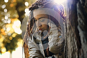 Happy dreadlocks fashionable girl posing in sunny forest