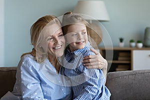 Happy dreamy grandkid hugging dreamy mature blonde grandmother with love,