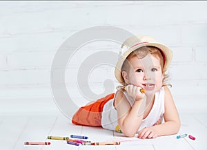 Happy dreamy little artist girl in a hat draws pencil