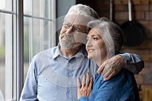 Happy dreamy mature couple hugging, thinking about good future together