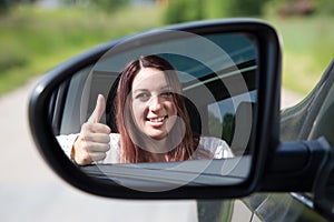 Happy driver showing thumbs up in the mirror