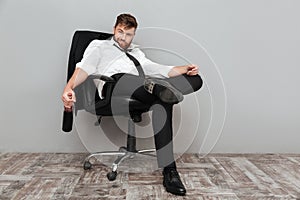 Happy drunk businessman sitting in office chair with bottle