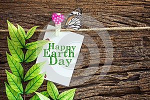 Happy Earth Day paper note hanging by red heart clips on wooden