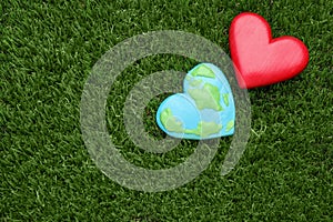 Happy Earth Day. Plasticine planet and decorative heart on green grass, flat lay with space for text