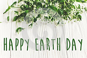 Happy earth day text sign on beautiful daisy flowers on rustic w