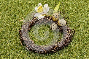 Happy Easter background. Quail eggs in a wicker wreath on fresh sunny green grass