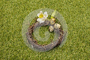 Happy Easter background. Quail eggs in a wicker wreath on fresh sunny green grass