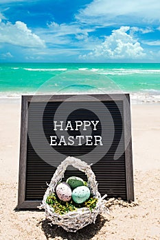 Happy Easter beach background with black board and basket