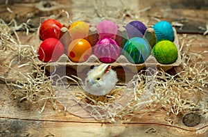 Happy Easter - beautiful, bright, very colorful hand-painted Easter eggs on a contrasting, raw, natural background from wooden pla