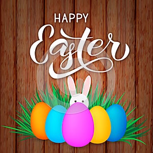 Happy Easter calligraphy lettering. Colorful easter eggs and bunny on wood background. Easy to edit vector template for spring