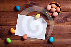 Happy easter card background, eggs and blank white paper on brown wooden table