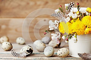 Happy Easter card with colorful flowers, feather and quail eggs on vintage wooden background. Beautiful spring composition.