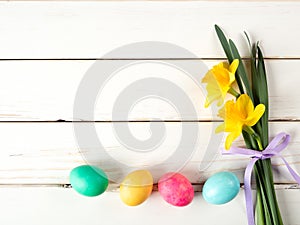 Happy Easter Card with Eggs in a row on Bottom with Daffodil Flowers on the side of White Shiplap Board Background with room or sp