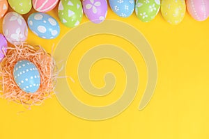 Happy easter celebration holiday. colourful pastel painted eggs in wicker basket nest decoration on a yellow background. Seasonal