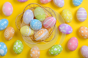 Happy easter celebration holiday. colourful pastel painted eggs in wicker basket nest decoration on a yellow background. Seasonal