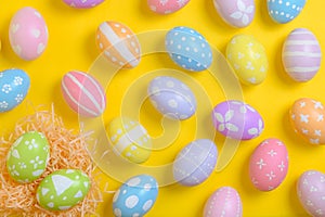 Happy easter celebration holiday. colourful pastel painted eggs in wicker basket nest decoration on a yellow background. Seasonal