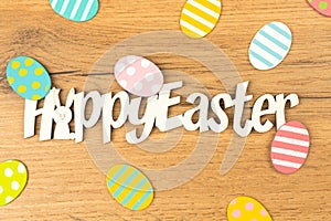 Happy easter celebration text and words with easter eggs on a wooden background. Spring holiday design, greetings