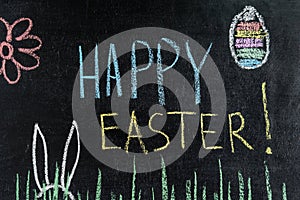 Happy Easter on chalk board, egg and spring flower, grass and easter bunny ears